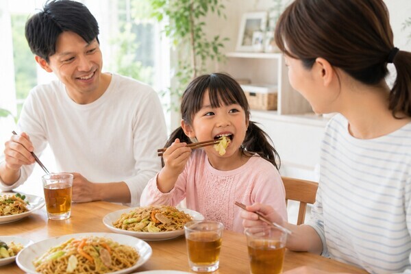 家族と会話を楽しみながら焼きそばを食べる子どもとお口の機能を育む食事風景